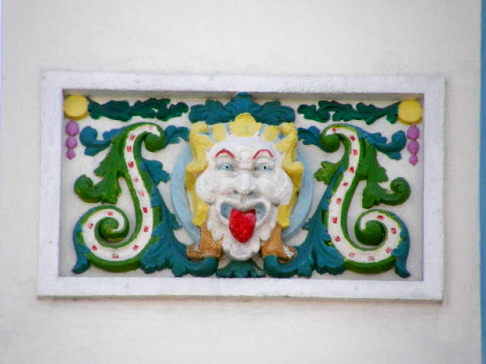 colorful bas relief of a clown eyes wide cheeks stylized and tongue from the middle to the bottom